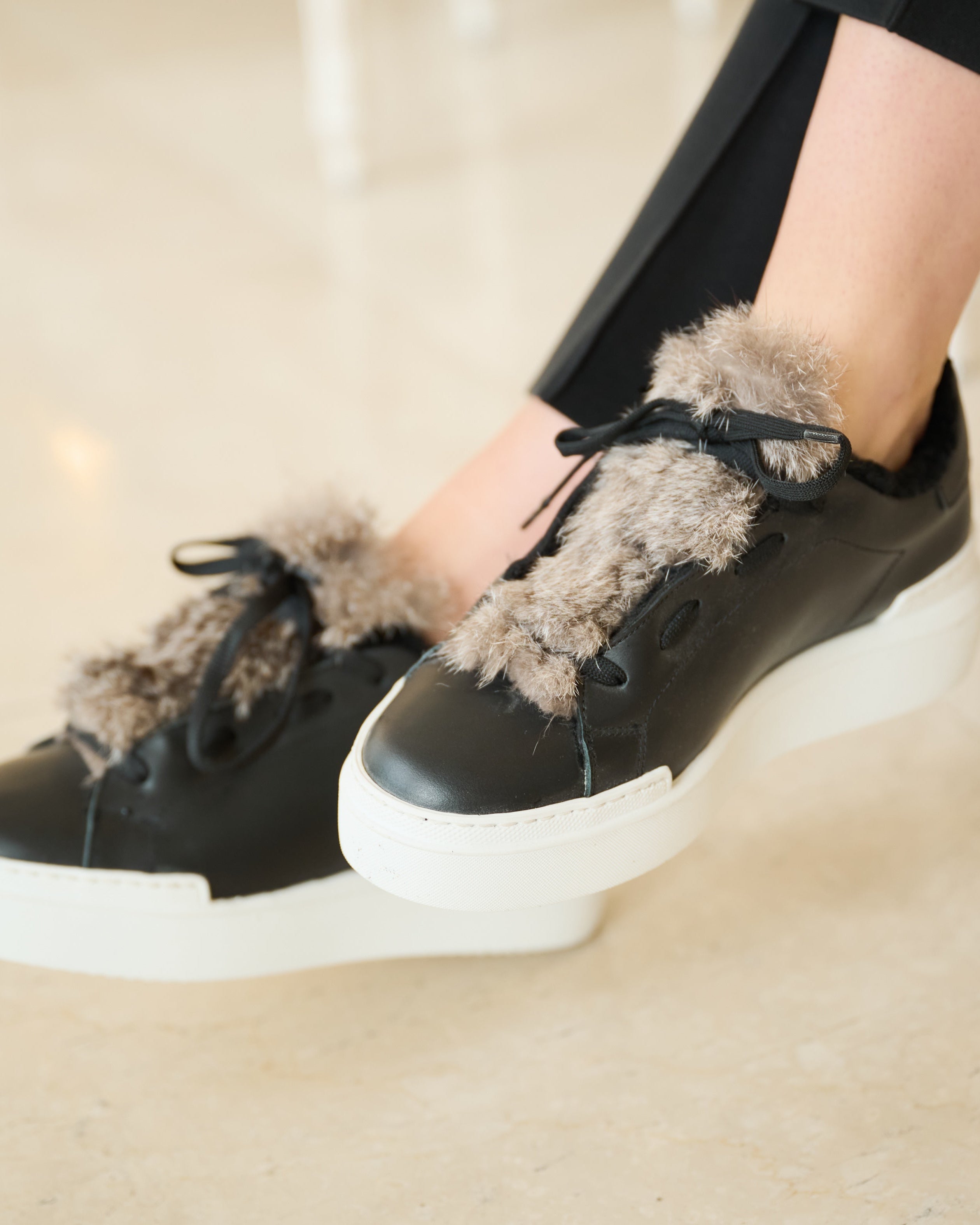 Nahaufnahme der naturgrauen Fellapplikation auf schwarzem Leder