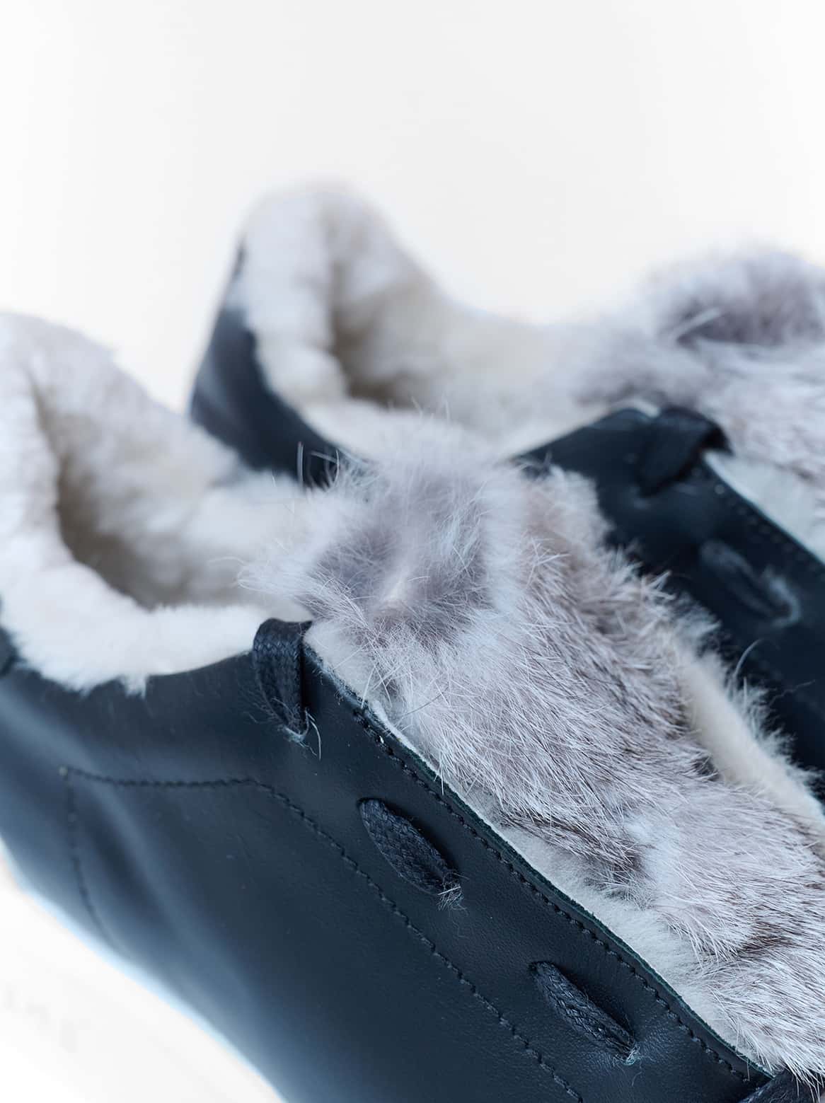 Nahaufnahme der naturgrauen Fellapplikation auf schwarzem Leder