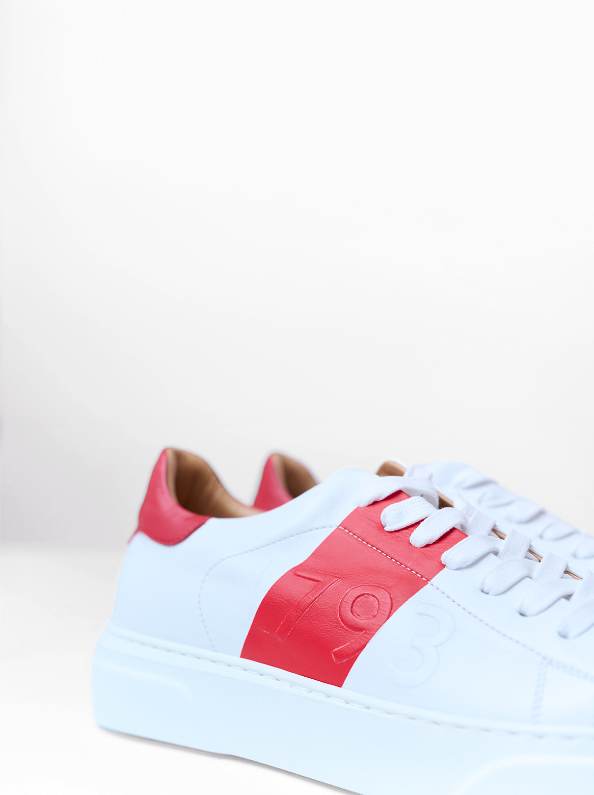 Seitliche Ansicht – Weißer Sneaker mit rotem Lederelement